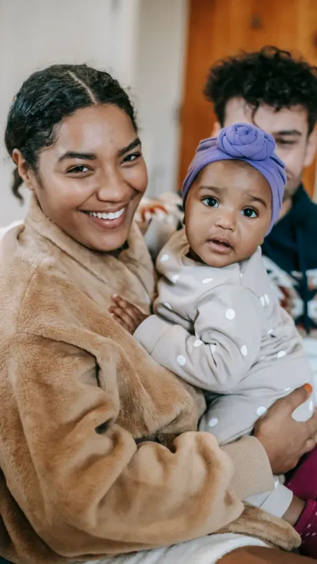 A parent holding her baby, both looking at camera.