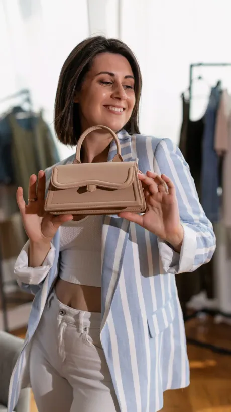 A creator holding a handbag up to camera while she talks about it.